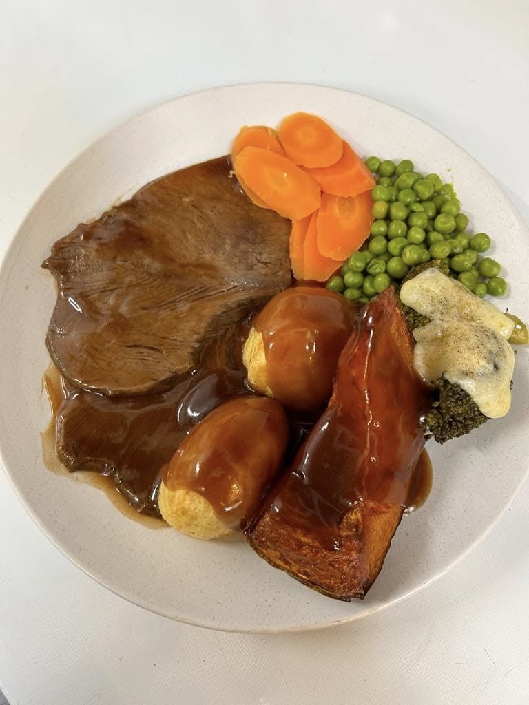 Sunday roast: sliced roast beef with gravy, roast potatoes, pumpkin and seasonal vegetables